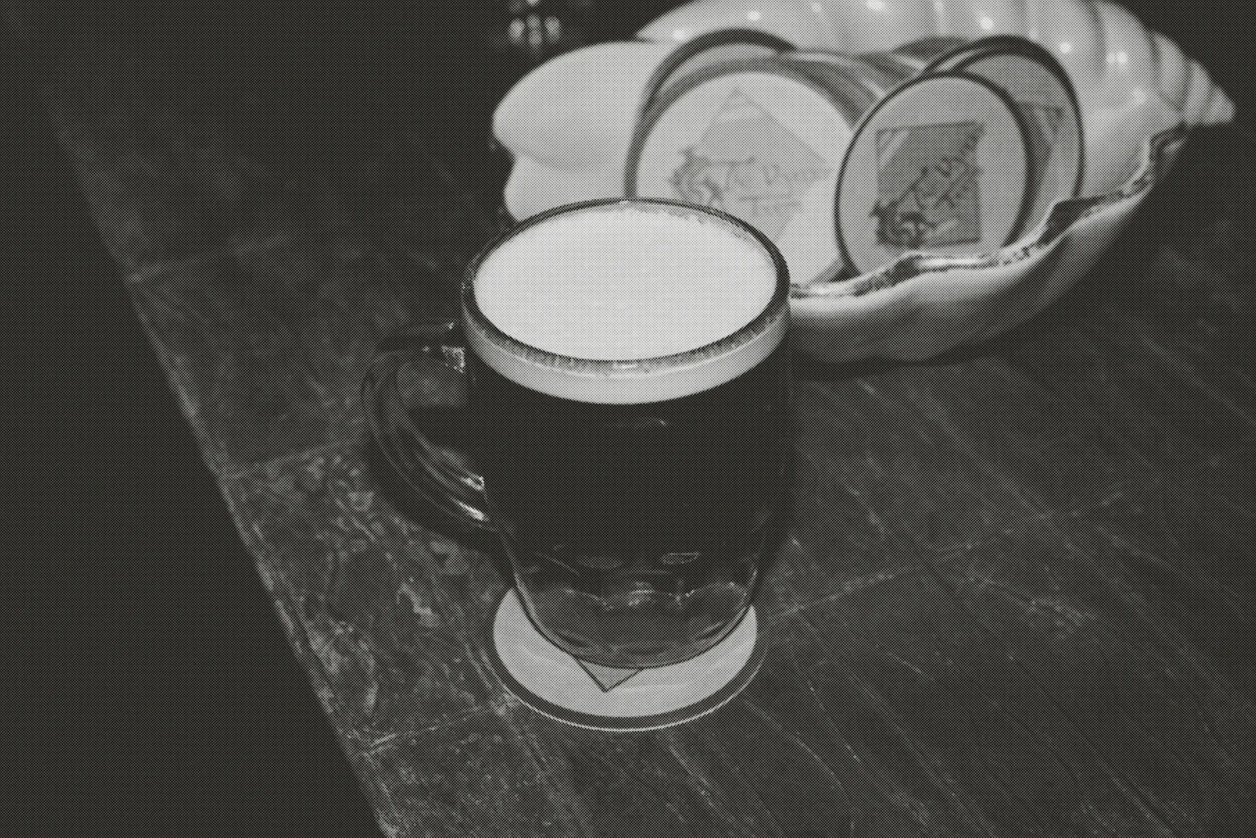 A dimpled beer mug on a branded coaster on the worn wooden bar.