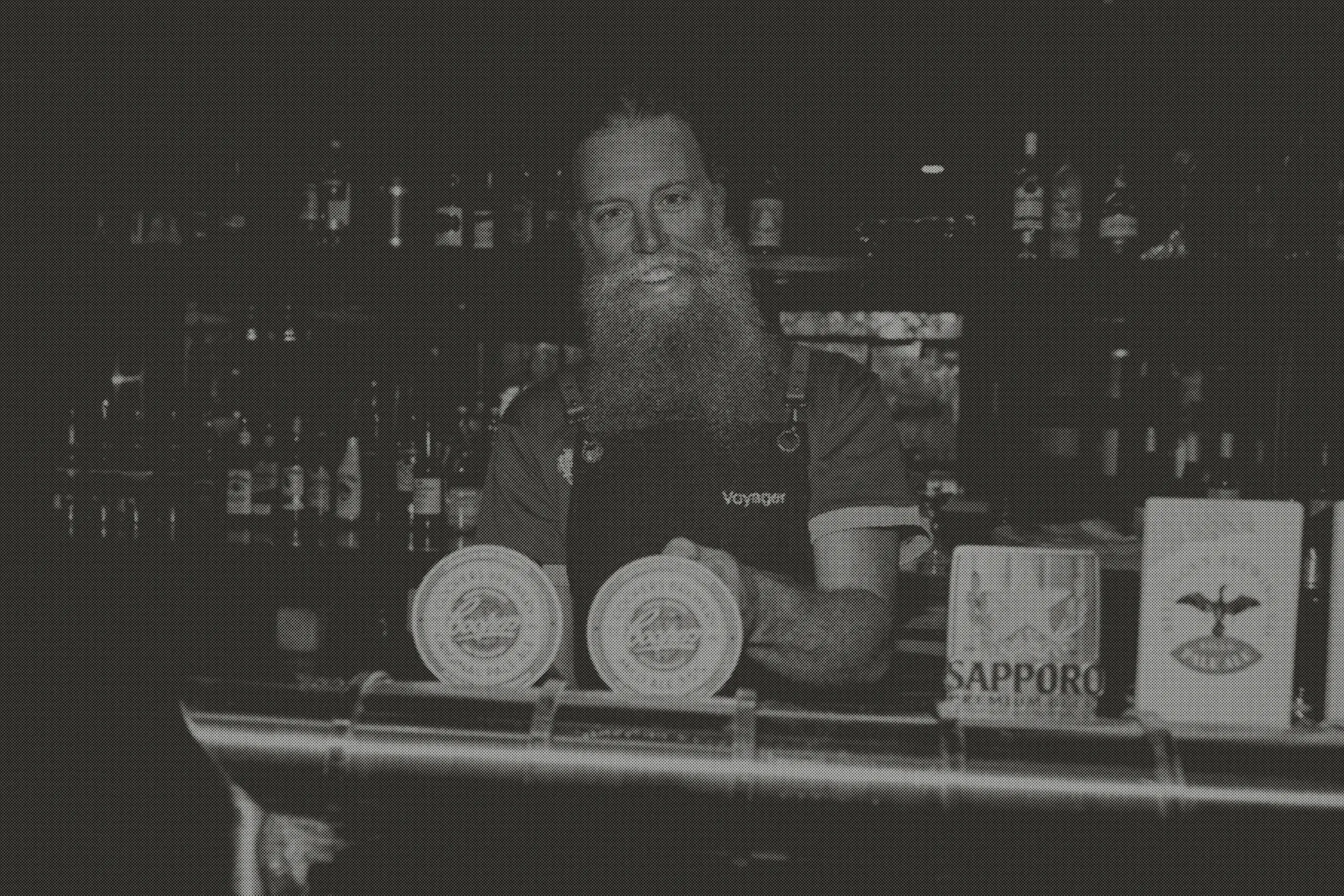 Nathan, bearded and grinning, behind the taps in his Voyager apron with Coopers and Sapporo badges on the font.